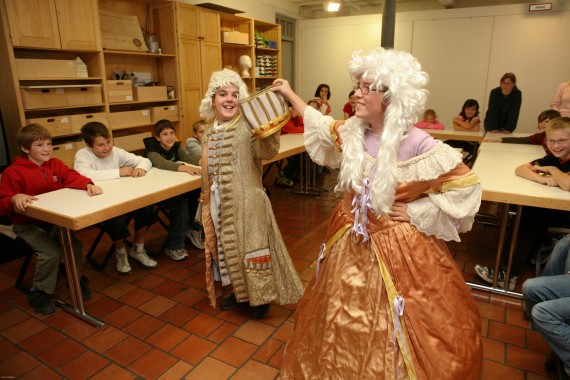 Ein Junge und eine Museumspädagogin tanzen in historischen Barockkostümen