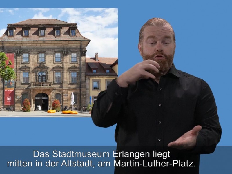 Gebärdensprachdolmetscher vor einem Foto des Stadtmuseums