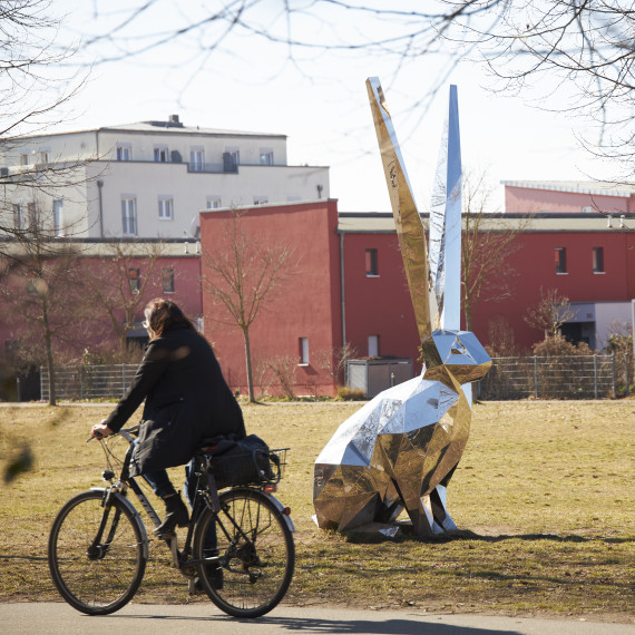 Radfahrer im Röthelheimpark vor der Hasenskulptur