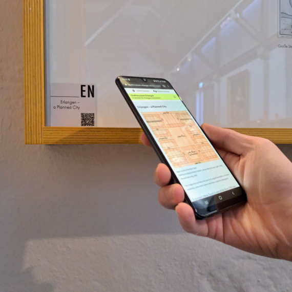 Ein Besucher mit Smartphone scannt einen QR-Code