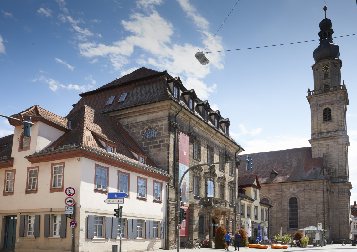 Das Bild zeigt drei Gebäude des künftigen Museumskarrees, das ehemalige Altstädter Rathaus sowie zwei Bürgerhäuser am Martin-Luther-Platz. Im Hintergrund ist die Altstädter Dreifaltigkeitskirche zu sehen.